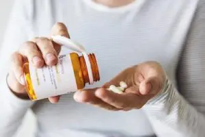 Lady pouring prescription drugs into her palm to relieve back pain