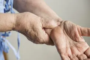 Elderly pressing her hands due to wrist pain.