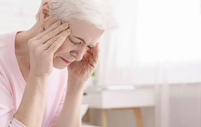 Senior woman touching her head due to headache.