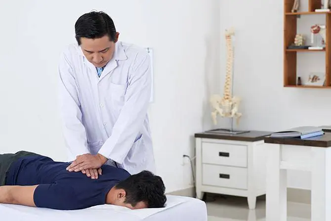 Doctor doing chiropractic work on a patient with back problems.