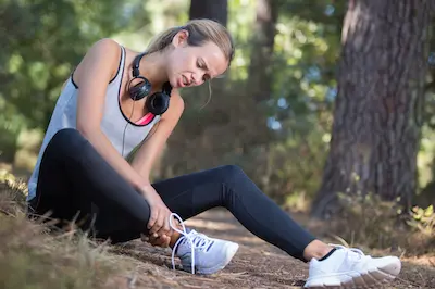 female runner holding her foot because of foot pain