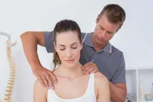 Chiropractor doing a treatment to female patient with neck pain.