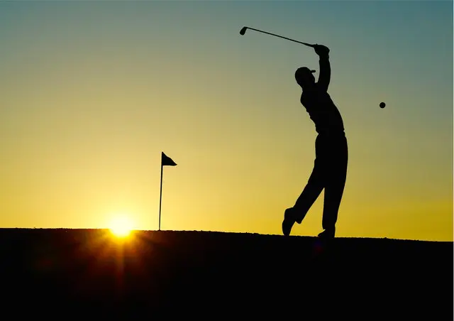 Silhouette of a man playing golf during sunset
