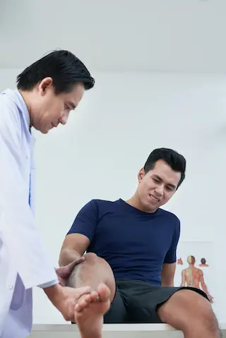 Chiropractor examining young male patient's knee