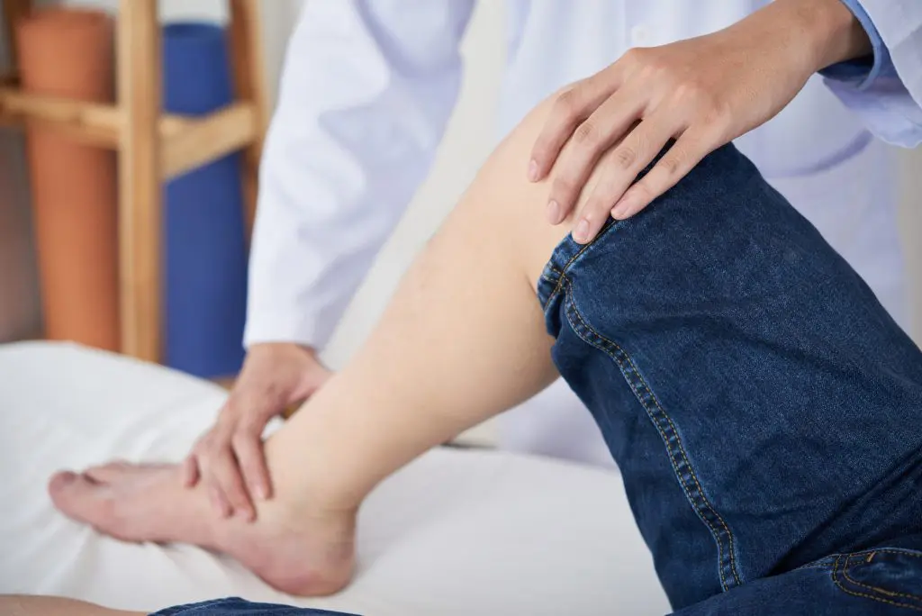 Doctor massaging a patient's leg due to pain.