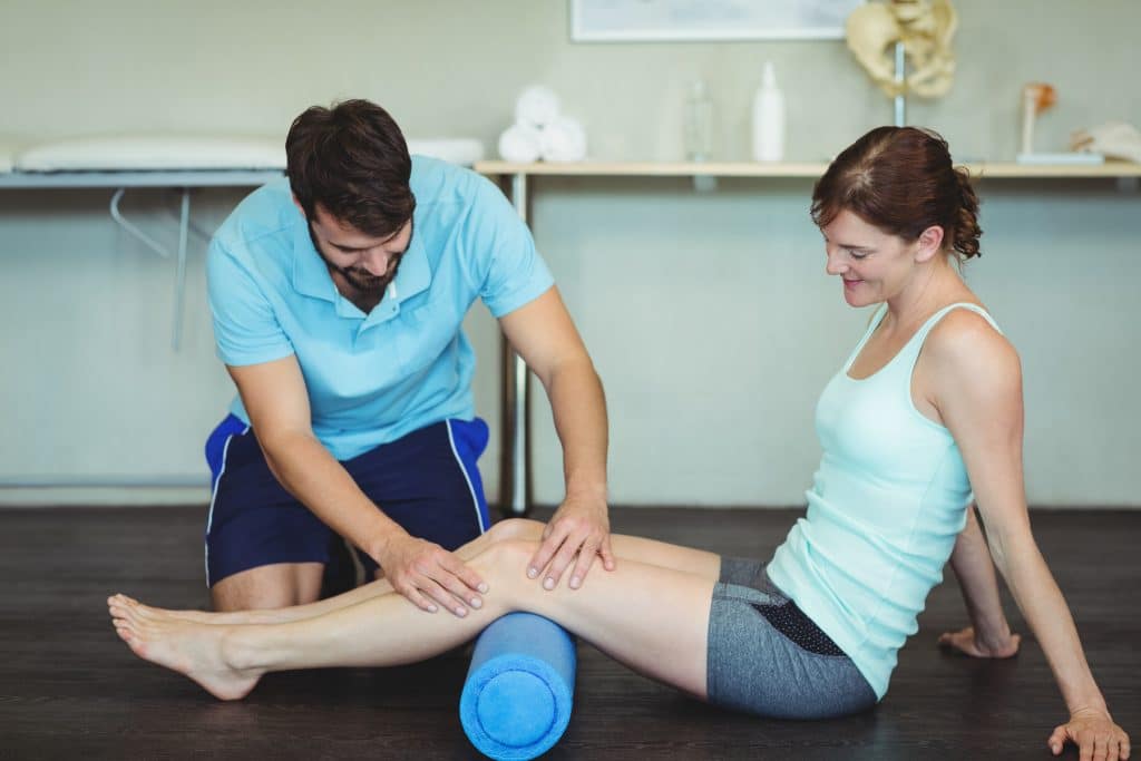 Therapist helping a female patient do knee exercise.