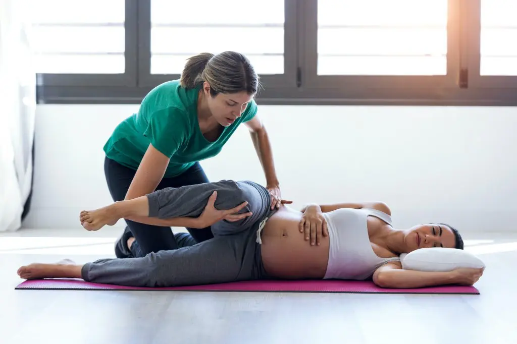 Physiotherapist helping a pregnant woman exercise for prenatal chiropractic care.