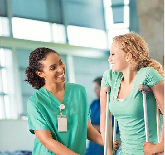 Physical therapist assisting a female patient in crutches for post surgery physical therapy.