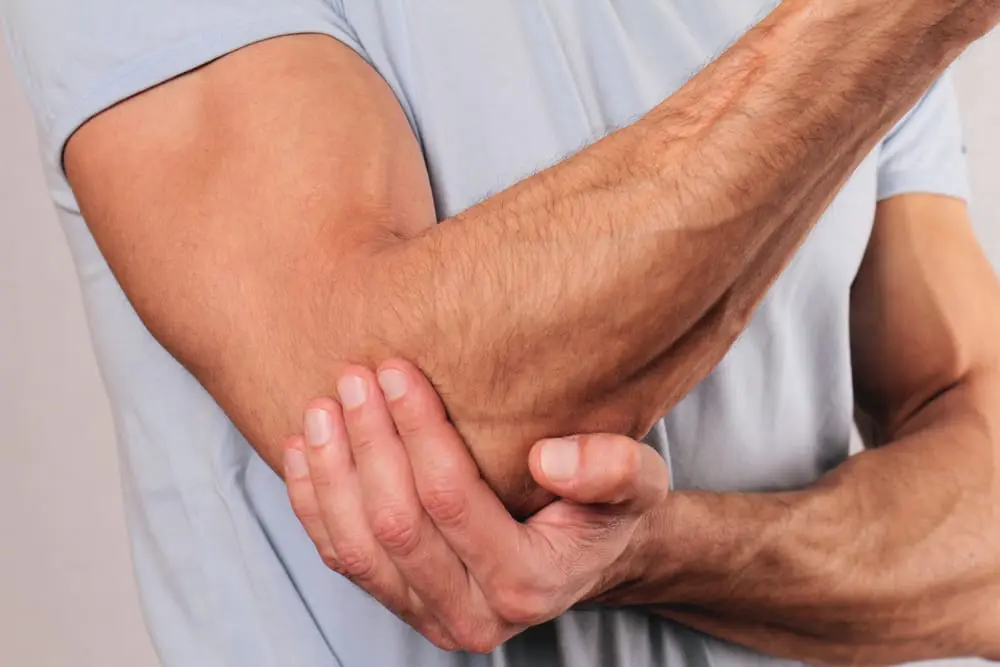 Mascular man holding his elbow with pain