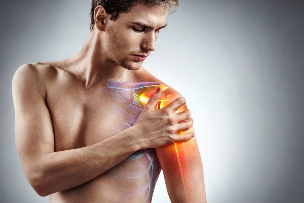 Man with shoulder pain holds left arm | pain management doctor in sugar land