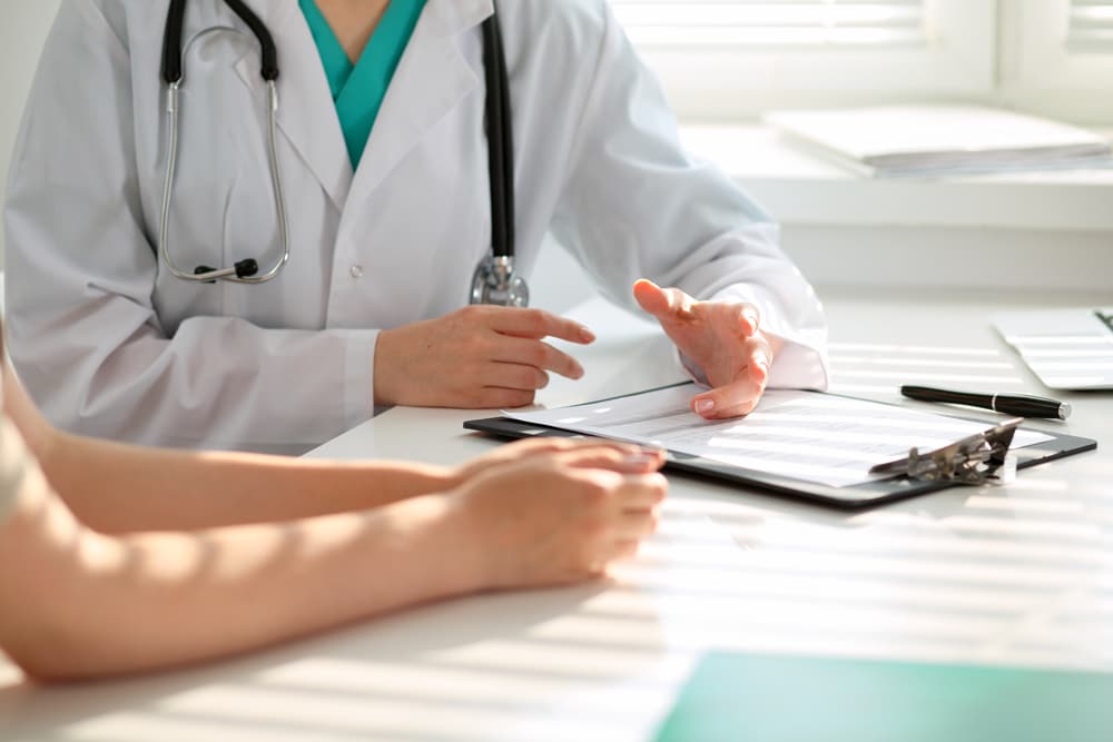 Pain management doctor sits with patient discussing findings