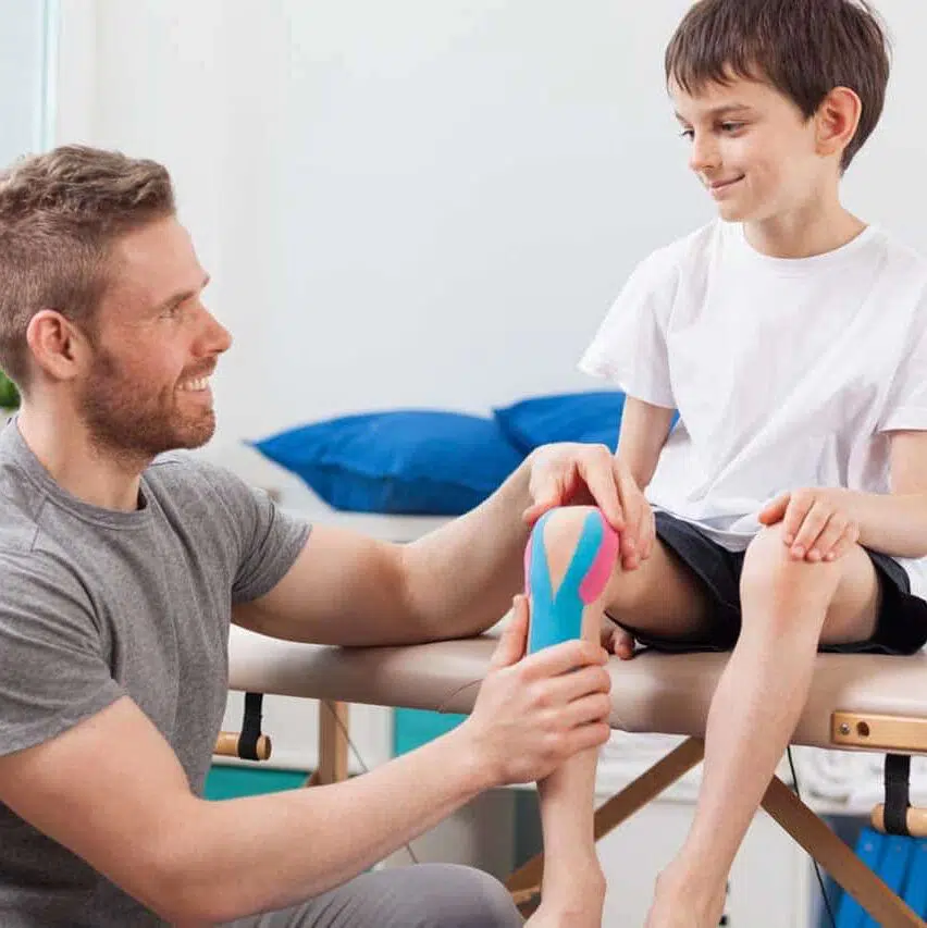 boy sitting on a drop table treated by a pediatric chiropractic in sugar land for knee injury