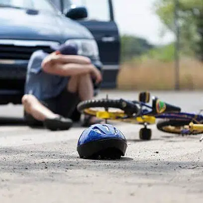 helmet and bike on the road that recently crashed on the car and a boy crying blurred on the background | pediatric chiropractic in sugar land