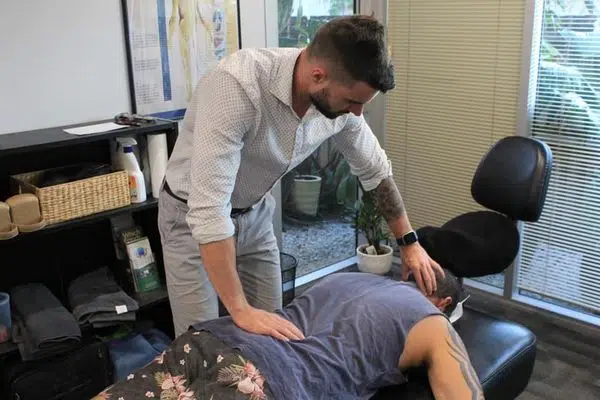 doctor conducting insured and covered chiropractic care treatment to male patient