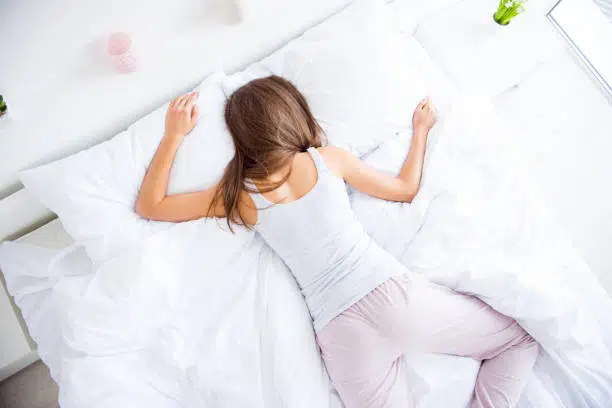 Woman is sleeping in her stomach position lying on the bed