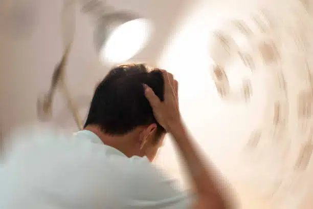  Man hands on his head feeling headache ,dizzy and spinning, caused by vertigo illness.