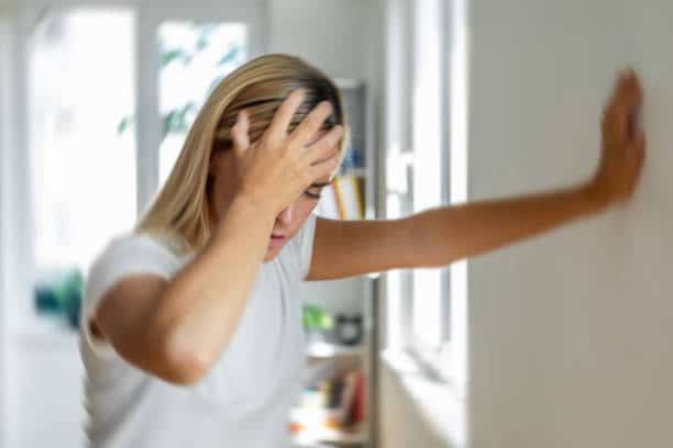 Woman holding her head feeling of too much pain caused by vertigo.