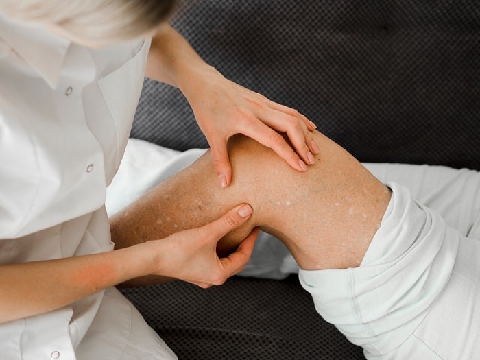 An experienced chiropractor performs knee joint mobilization therapy to help a patient suffering from knee arthritis