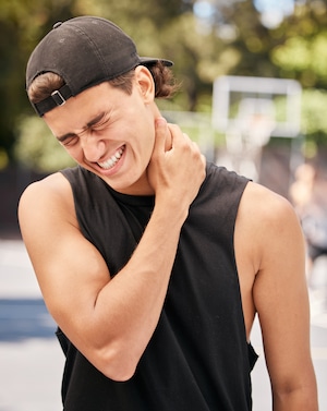 A man wearing a black shirt having a neck pain