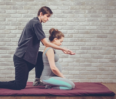 therapist at clinic giving neck massage to pregnant patient