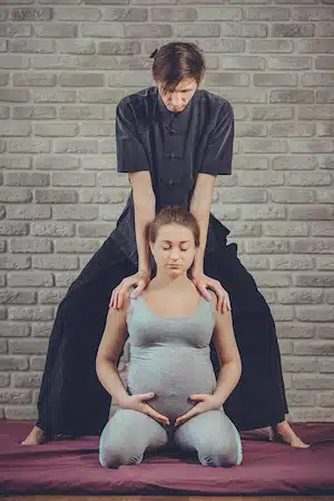 pregnant woman getting massage at clinic for treating Lower Back Pain