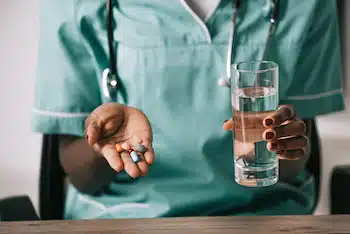 nurse holding prescribed medication and a glass of water | benefits of physical therapy