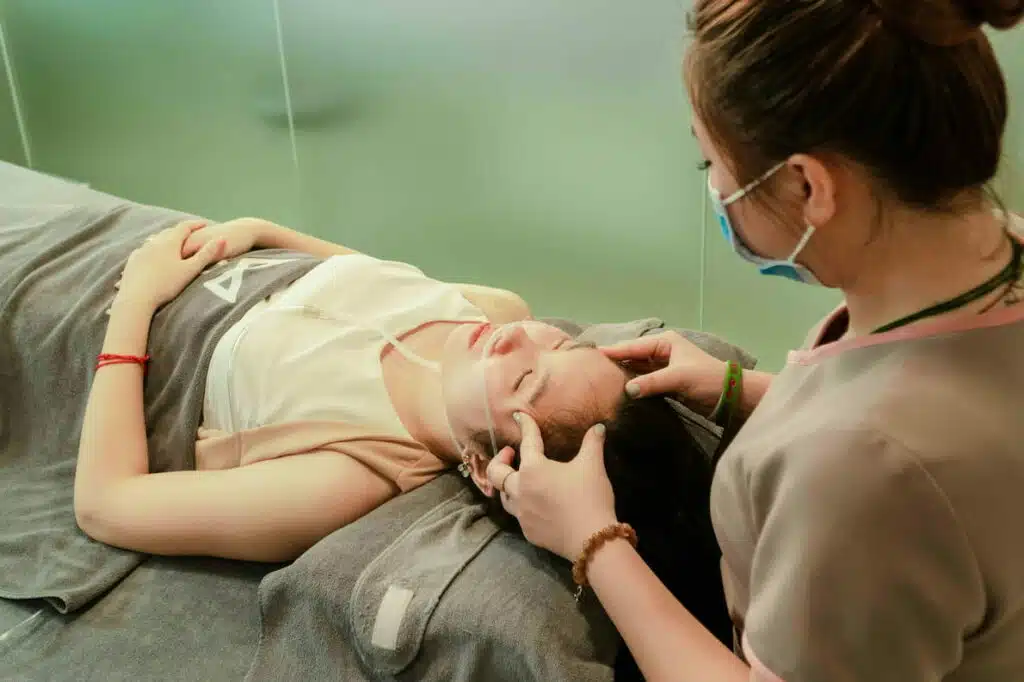 A Woman Lying Down while Having Her Head Massage by a Therapist